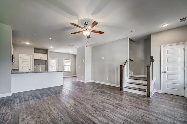 unfurnished living room featuring dark hardwood / wood-style flooring, ceiling fan, and sink