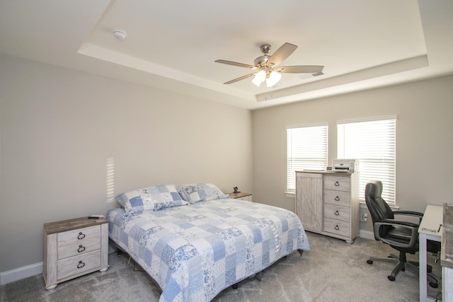 bedroom featuring ceiling fan, a raised ceiling, and light colored carpet