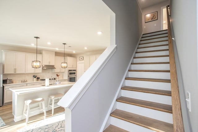 staircase featuring hardwood / wood-style flooring and sink