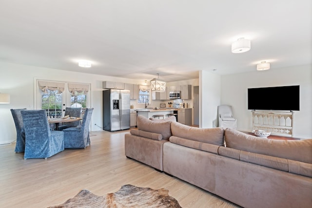 living room with french doors, light hardwood / wood-style floors, and a notable chandelier