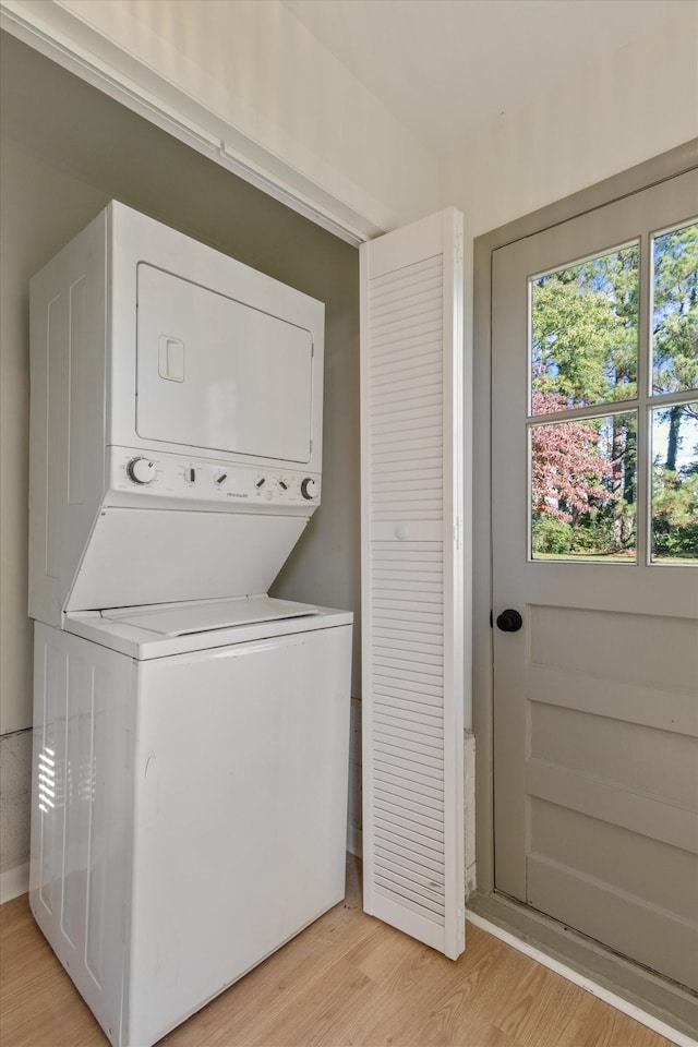 clothes washing area featuring light wood-type flooring and stacked washer / dryer