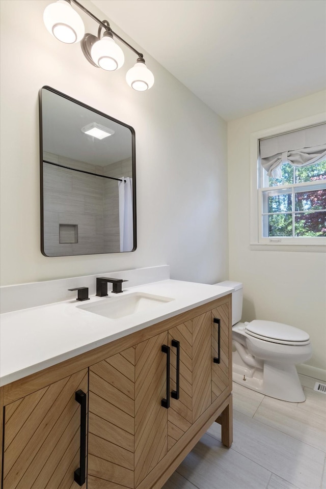 bathroom with walk in shower, tile patterned flooring, vanity, and toilet