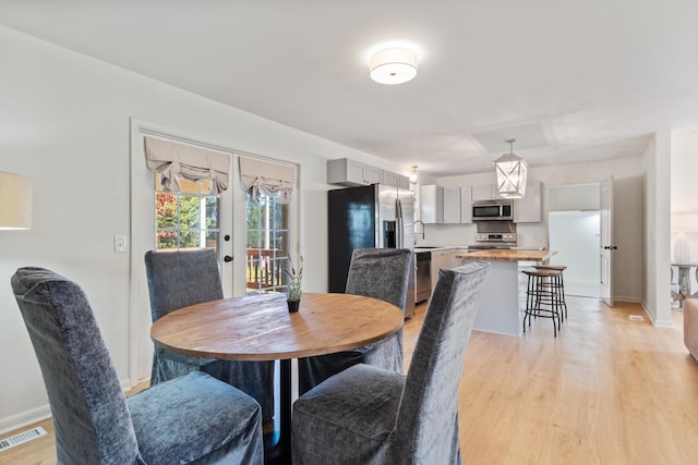 dining space featuring french doors, light hardwood / wood-style floors, and sink