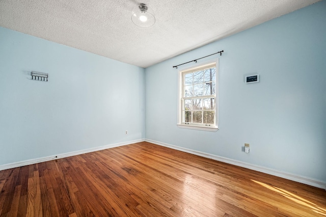 spare room with a textured ceiling and hardwood / wood-style flooring