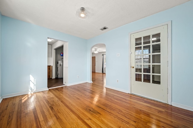 spare room with a textured ceiling, hardwood / wood-style flooring, ceiling fan, and electric water heater