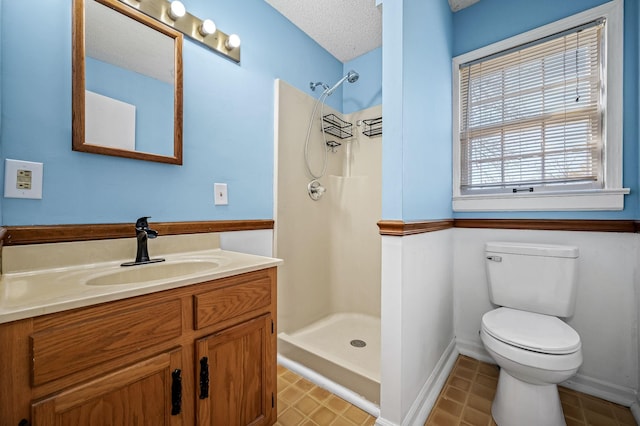 bathroom with a shower, vanity, a textured ceiling, and toilet