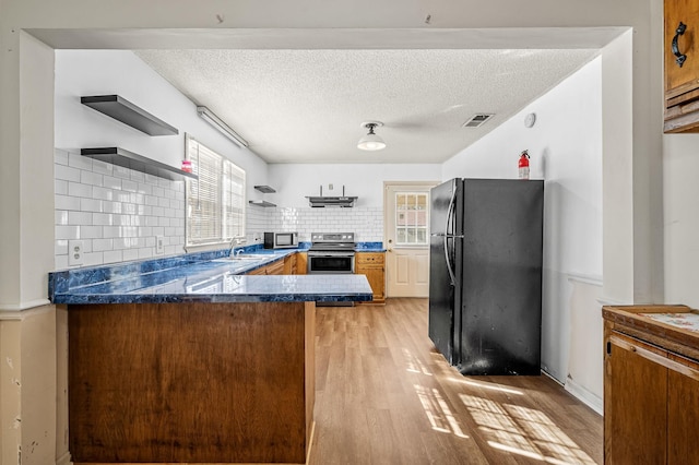 kitchen featuring sink, stainless steel appliances, tasteful backsplash, kitchen peninsula, and light wood-type flooring