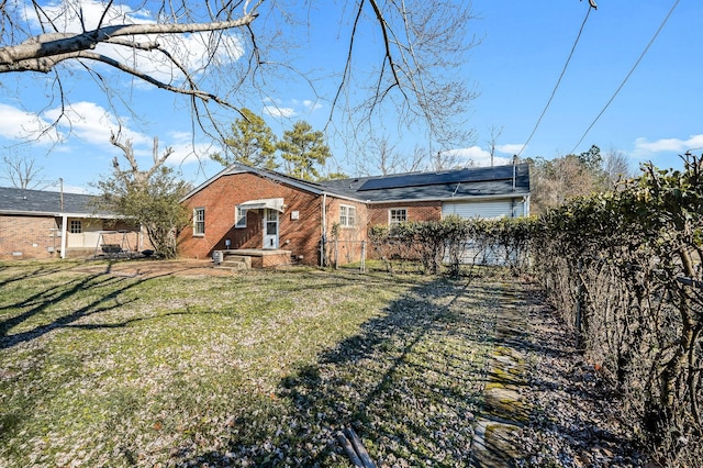 rear view of property featuring solar panels and a yard