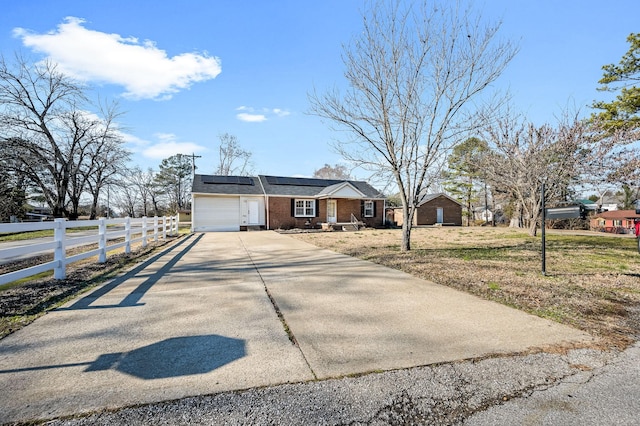 ranch-style home featuring a garage, a front yard, and solar panels