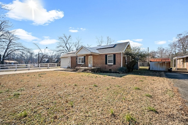 view of front of home with solar panels, a front lawn, and a storage shed