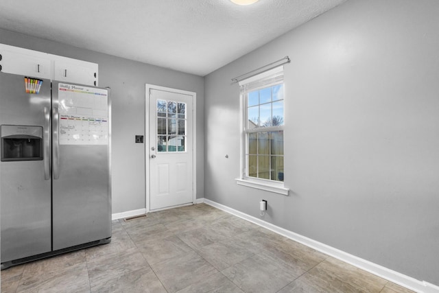 kitchen with stainless steel fridge and white cabinetry