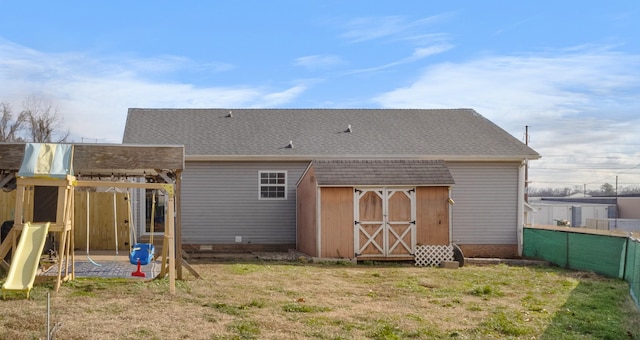 back of property featuring a lawn and a playground