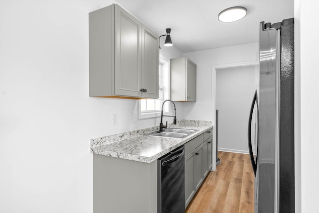 kitchen with dishwasher, sink, stainless steel fridge, light wood-type flooring, and gray cabinetry