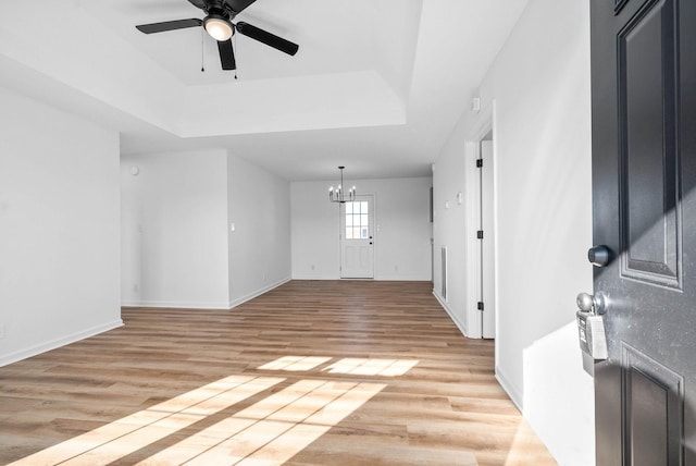 entryway featuring a raised ceiling, ceiling fan with notable chandelier, and light hardwood / wood-style floors