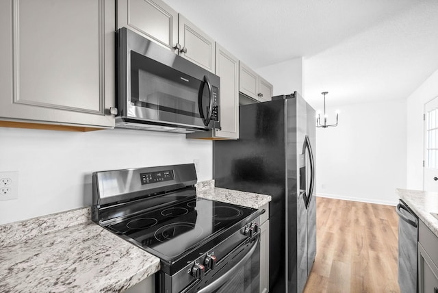 kitchen featuring stainless steel appliances, hanging light fixtures, a chandelier, light wood-type flooring, and gray cabinetry