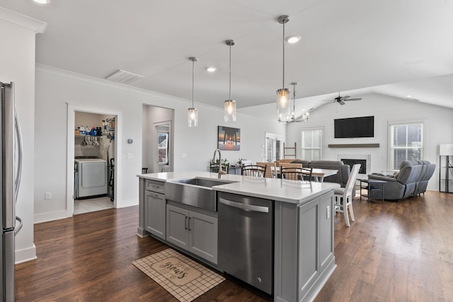 kitchen with appliances with stainless steel finishes, decorative light fixtures, ceiling fan, and an island with sink