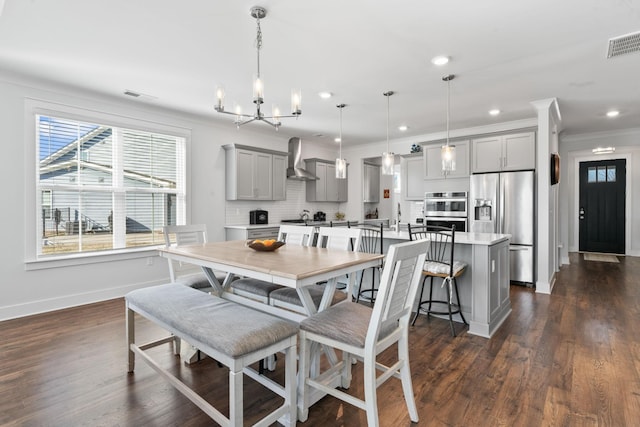 kitchen featuring pendant lighting, gray cabinets, wall chimney range hood, and appliances with stainless steel finishes