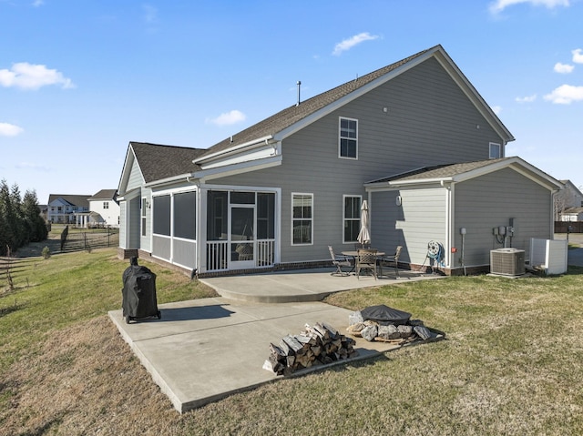 rear view of property featuring a sunroom, a patio, an outdoor fire pit, and a lawn