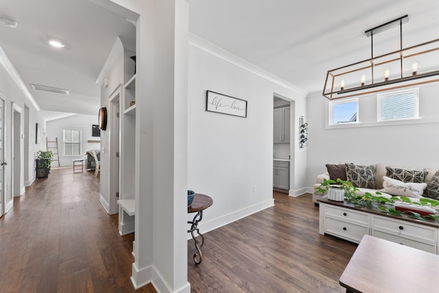 hall with a notable chandelier, dark hardwood / wood-style floors, and ornamental molding