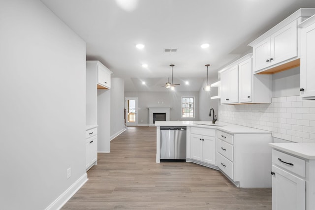 kitchen with a sink, a ceiling fan, stainless steel dishwasher, backsplash, and a glass covered fireplace