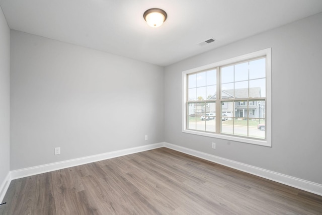 empty room with visible vents, baseboards, and wood finished floors