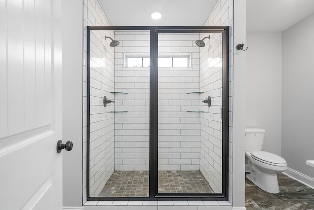 bathroom featuring toilet, a stall shower, and baseboards