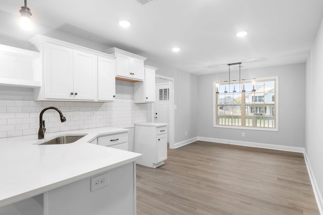 kitchen with a sink, white cabinets, hanging light fixtures, decorative backsplash, and open shelves