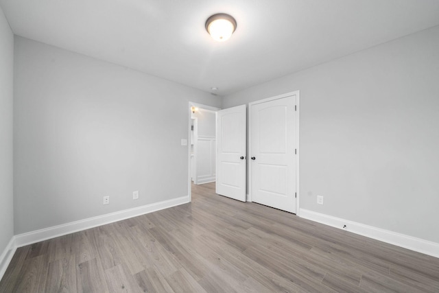 unfurnished bedroom with a closet, baseboards, and wood finished floors