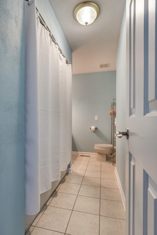 bathroom featuring tile patterned floors, toilet, and a textured ceiling