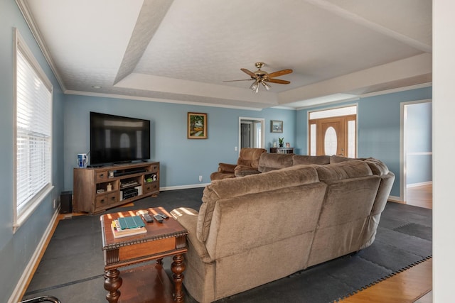 living room with ceiling fan, a raised ceiling, and ornamental molding