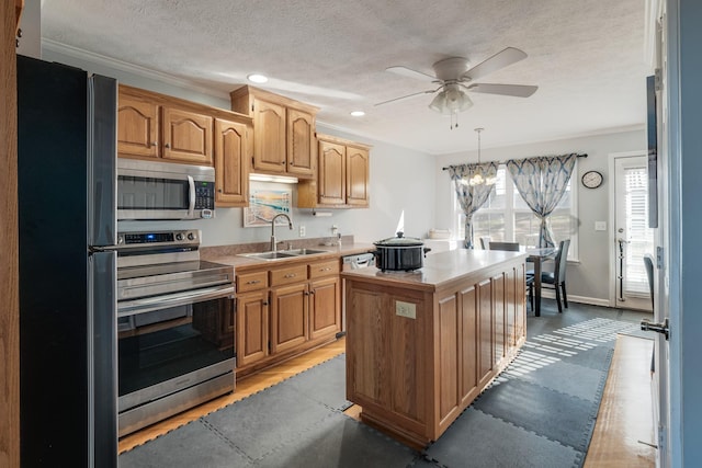 kitchen with ceiling fan with notable chandelier, a textured ceiling, stainless steel appliances, sink, and a center island