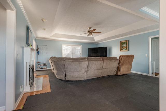 living room featuring a tray ceiling, ceiling fan, and ornamental molding