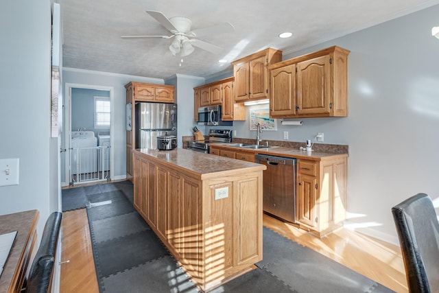 kitchen with crown molding, sink, a kitchen island, stainless steel appliances, and washing machine and clothes dryer