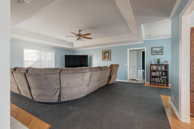 living room featuring ceiling fan, wood-type flooring, crown molding, and a tray ceiling