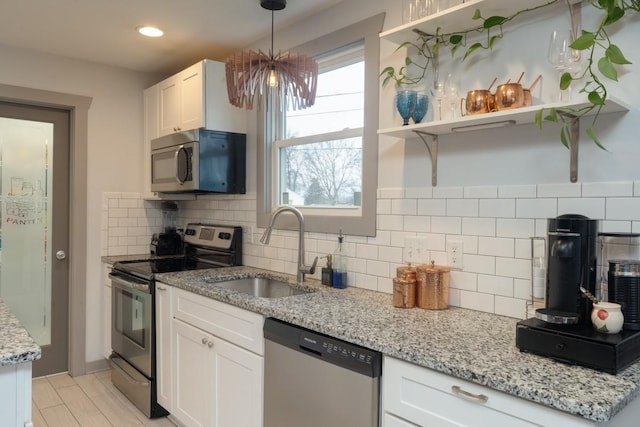 kitchen featuring decorative backsplash, light stone countertops, stainless steel appliances, sink, and white cabinets