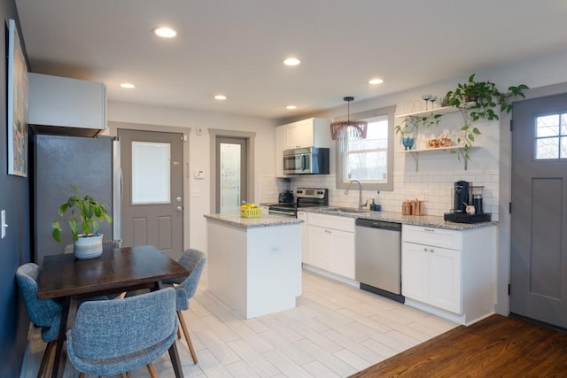 kitchen featuring white cabinetry, sink, stainless steel appliances, decorative light fixtures, and decorative backsplash