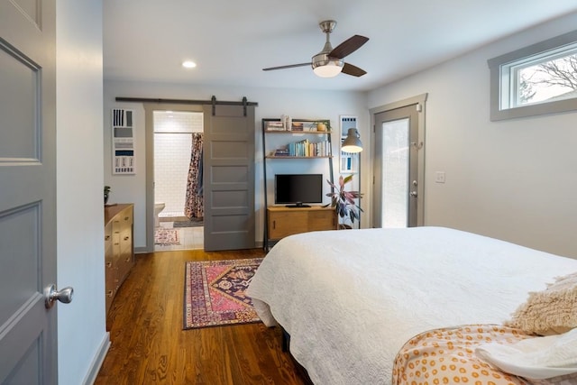 bedroom featuring a barn door, ceiling fan, and dark hardwood / wood-style floors