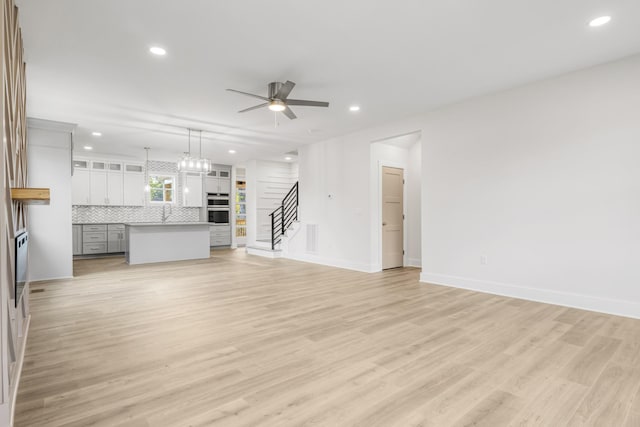 unfurnished living room featuring ceiling fan and light wood-type flooring