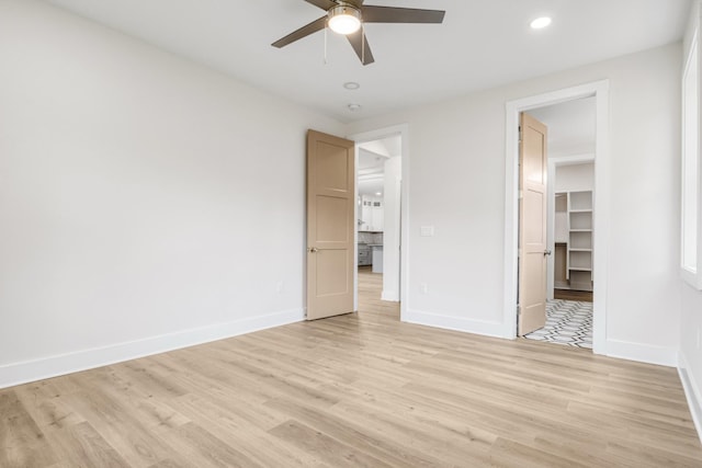 unfurnished bedroom featuring a walk in closet, ceiling fan, a closet, and light hardwood / wood-style floors