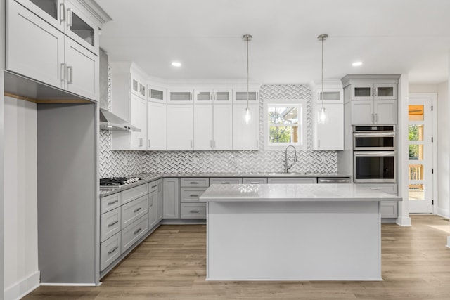 kitchen with appliances with stainless steel finishes, sink, decorative light fixtures, white cabinets, and a kitchen island