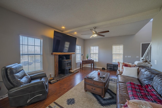 living room with a wood stove, ceiling fan, dark hardwood / wood-style floors, and a textured ceiling