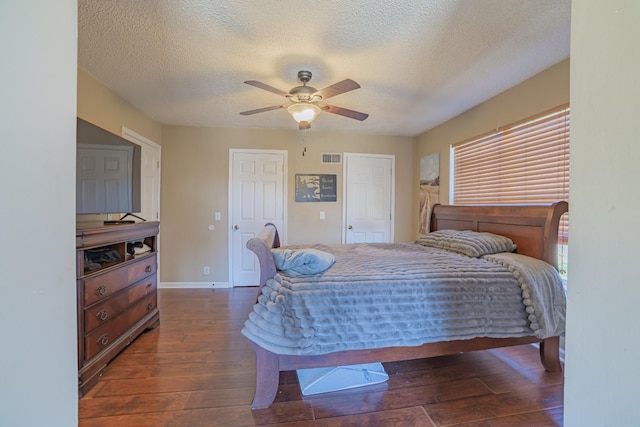 bedroom with a textured ceiling, dark hardwood / wood-style floors, and ceiling fan