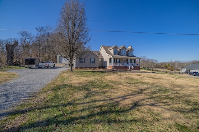 cape cod home featuring covered porch, an outbuilding, a garage, and a front yard