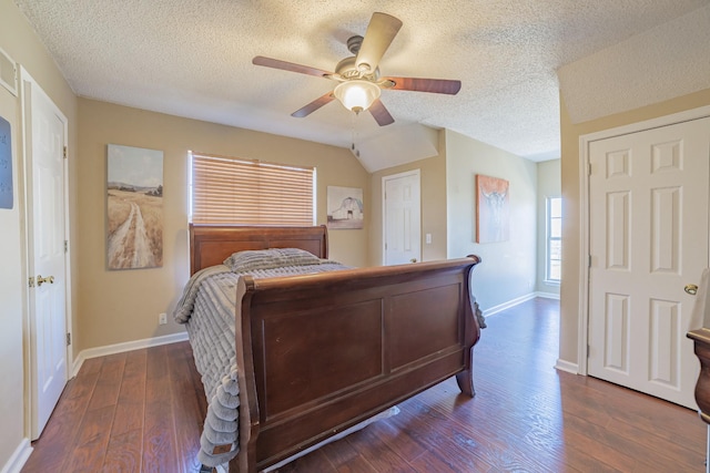 bedroom with ceiling fan, vaulted ceiling, a textured ceiling, and dark wood-type flooring