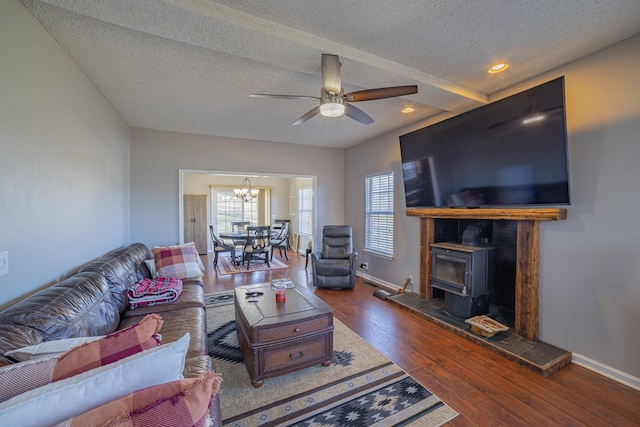 living room featuring a wood stove, ceiling fan with notable chandelier, dark hardwood / wood-style floors, and a textured ceiling