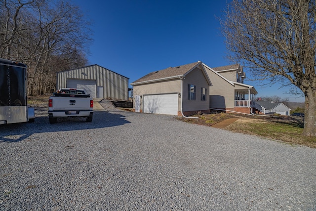 view of property exterior with covered porch, an outbuilding, and a garage