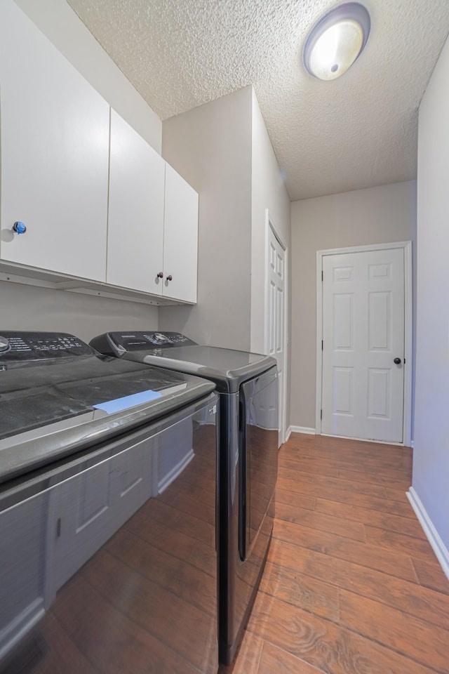 washroom featuring cabinets, a textured ceiling, hardwood / wood-style flooring, and washer and dryer