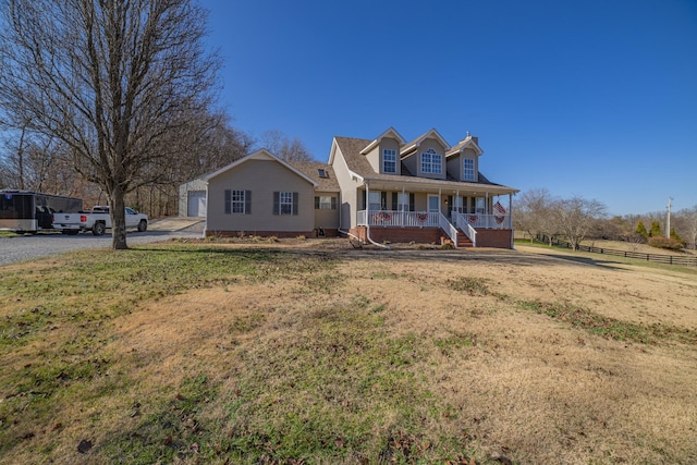 cape cod home with a porch and a front lawn