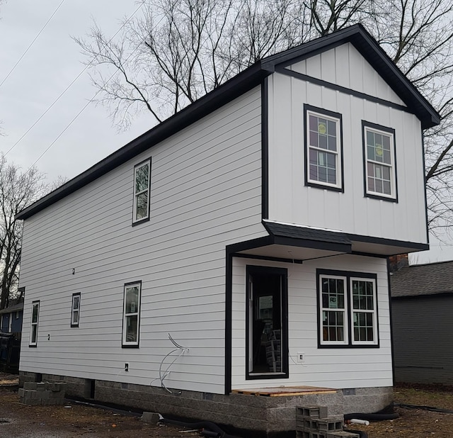 back of property with crawl space and board and batten siding