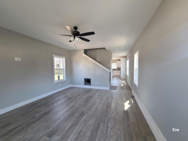 unfurnished living room with dark wood-type flooring, baseboards, and ceiling fan